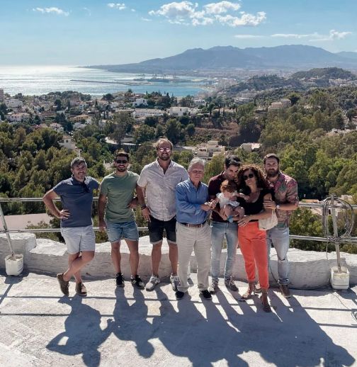 Part of the Flow81 team posing for a casual group photo with the bay of Málaga in the background